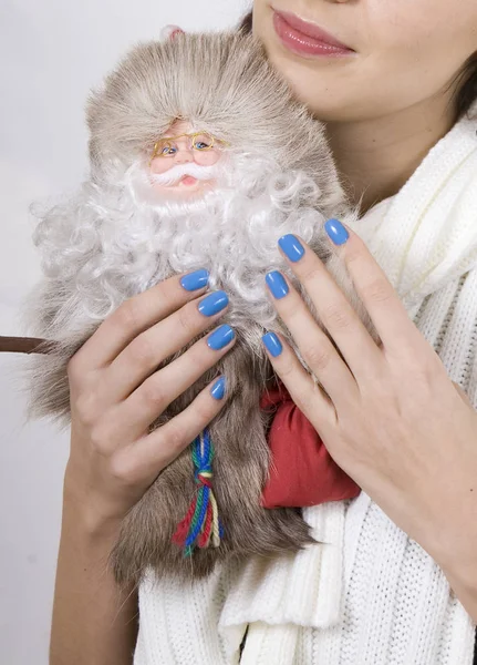 Portrait of young woman with toy Santa. Hands with beautiful manicure closeup.