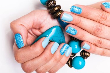 Bir boncuk holding kadın mavi manikürlü tırnaklar.