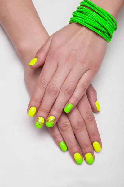 Kadın yeşil ve sarı manikürlü tırnaklar 