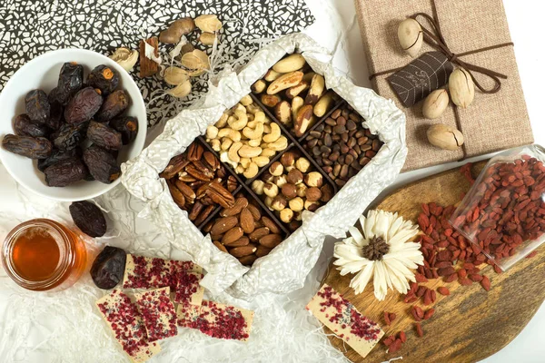 Sağlıklı beslenme. Tarihleri, Goji Karpuzu, doğal beyaz çikolata, bal ve çeşitli fındık. Kompozisyon üstten görünüm. Düz yatıyordu.