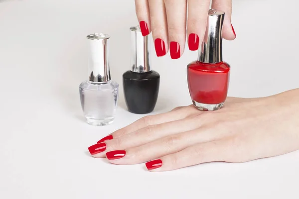 Manicure and Hands Spa. Beautiful manicured woman's hands with red nail polish and colorful nail polish bottles.