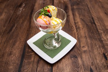 Tahta masadaki bardakta nane yapraklı üç kepçe dondurma..