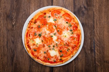 Klasik İtalyan pizzası ahşap bir masada.