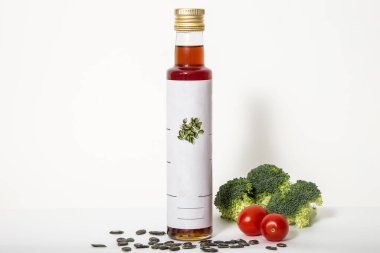 Balkabağı tohumu yağı karışımı. Hafif arkaplanda tohum yağı, brokoli ve kiraz domatesleri..