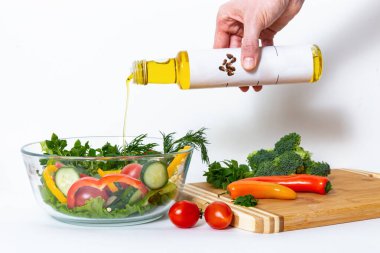 Keten tohumu yağı ve sebzeli kompozisyon: hafif arkaplanda kiraz domatesleri, tatlı biber, marul yaprakları, dereotu, brokoli ve fesleğen yaprağı. 