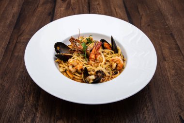 Tahta bir masada servis edilen midyeli ve kraliyet karidesli deniz mahsullü makarna.. 