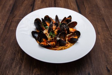 Tahta bir masada servis edilen midye ve domatesli deniz ürünleri spagettisi.. 