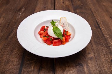 Tahta bir masanın üzerinde domatesli taze Burrata peyniri..