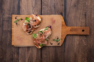 Ciabatta, Parma jambonu, Gorgonzola peyniri, fındık, armut, hardal sosu ve ahşap bir tahtada karışık salata..