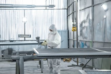 Elinde endüstriyel spreyler olan bir boyacı..