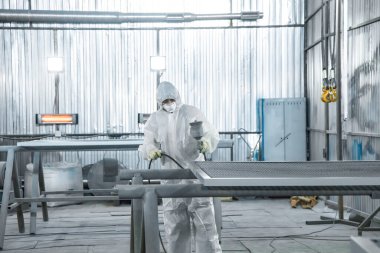 Elinde endüstriyel spreyler olan bir boyacı..