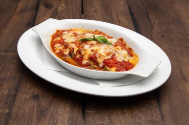 Beyaz tabakta servis edilen peynirle kaplı etli lezzetli lazanya. İtalyan mutfağı.