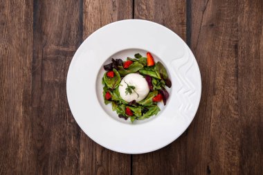 Taze İtalyan buratta peyniri karışık salata yaprakları ve ahşap bir masada bir tabakta çilek. İtalyan mutfağı.