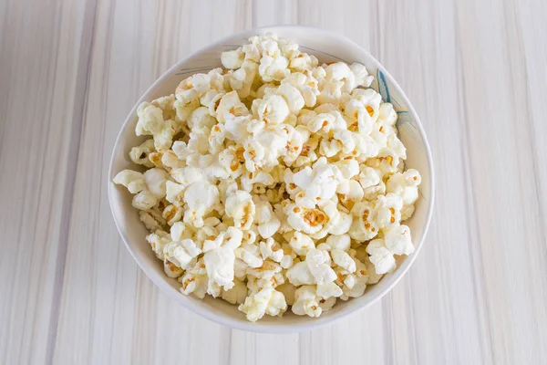 Popcorn in white bowl closeup on wood table — Stock Photo, Image