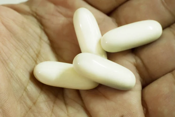 The White capsules on hand image close up — Stock Photo, Image