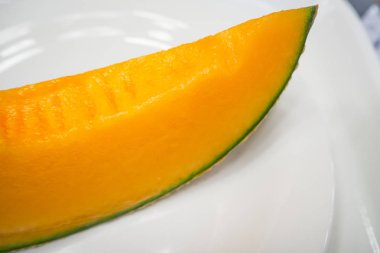 Beyaz tabak resmin üzerine dilimlenmiş taze Japon kavun yakın çekim.