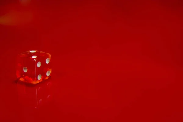 Το κόκκινο ζάρι σε φωτεινό κόκκινο γυαλιστερό φόντο. — Φωτογραφία Αρχείου