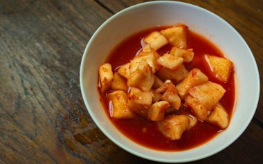 Kore Turpu Kimchi beyaz kâse içinde ahşap masa üzerinde yemek içeriyor..