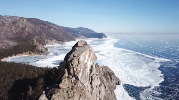 美しい深い青色の氷の空中展望ロシアの晴れた冬の日にドローンで撮影された上から凍ったバイカル湖の表面と海岸 — ストック動画