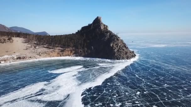 美しい深い青色の氷の空中展望ロシアの晴れた冬の日にドローンで撮影された上から凍ったバイカル湖の表面と海岸 — ストック動画