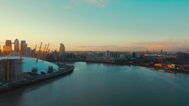 Широкоугольная воздушная съемка реки Темзы, полуострова Гринвич и финансового центра Канари-Уорф на закате в Лондоне, Англия, Великобритания — стоковое видео