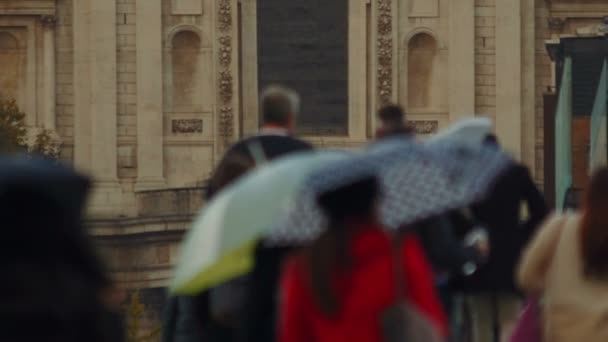 Una signora in rosso che cammina lungo un gruppo di persone anonime nel centro di Londra in un giorno di pioggia — Video Stock