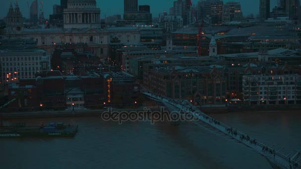 Tilting shot showing the Millennium Bridge and St Pauls Cathedral during the blue hour in London, England, UK — Stock Video