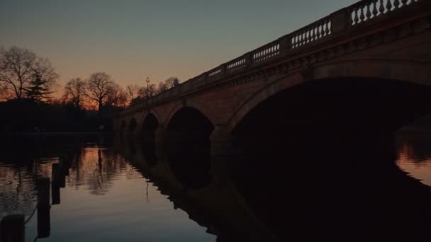 Zonsondergang schilderachtig uitzicht op een stenen brug en de Serpentine in Hyde Park, Londen, Engeland, Verenigd Koninkrijk — Stockvideo