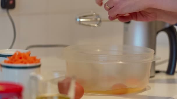 Auténtica toma de comida que muestra a una joven rompiendo huevos en preparación para un pastel de zanahoria — Vídeos de Stock