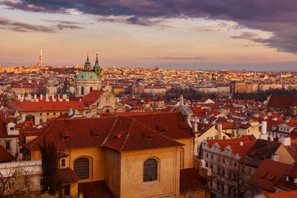 A rooftop early night view of Prague Old Town district (Mala Strana) featuring street lights and the Zizkov Television Tower in the distance (Prague, Czech Republic/Czechia).