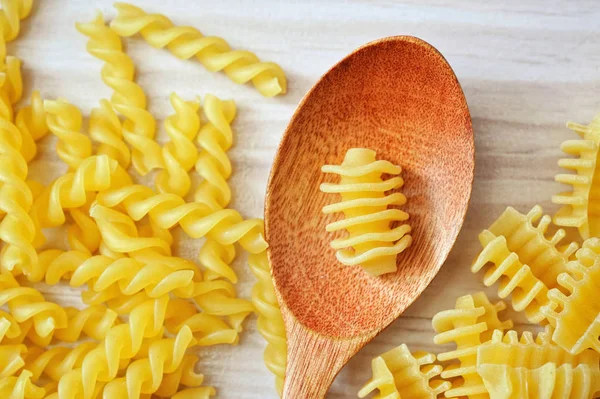 Bodegón de cuchara de madera sobre mesa blanca con pasta — Foto de Stock