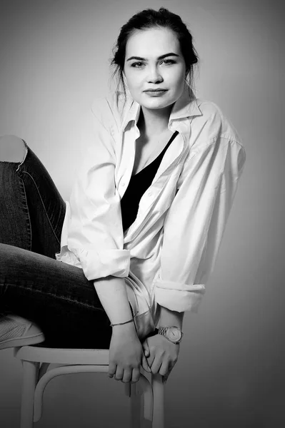 Jeune européen attrayant modèle de mode sexy beaux yeux pose en jeans et chemise sur chaise — Photo