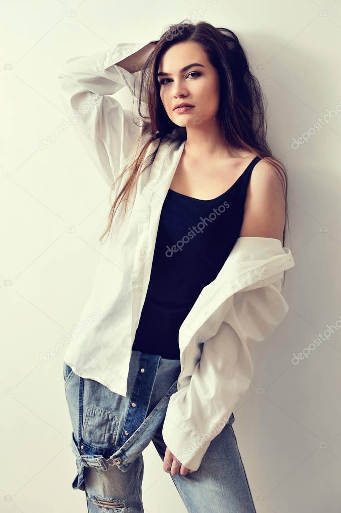 Young European attractive fashion model is posing in jeans overalls and shirt