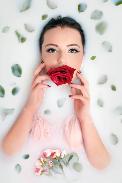 Κορίτσι παίρνει ένα λουτρό με γάλα και τριαντάφυλλο λουλούδι στα χείλη σου — Φωτογραφία Αρχείου