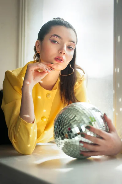 Jeune femme avec maquillage d'épice coloré lumineux et boule disco miroir — Photo