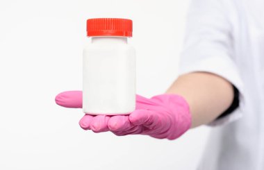 white jar of pills with red cover in hand in pink gloves.