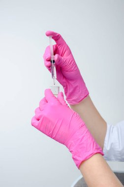 Syringe in hand in medical pink glove. Injectable vaccination. Medicine. Medical procedures