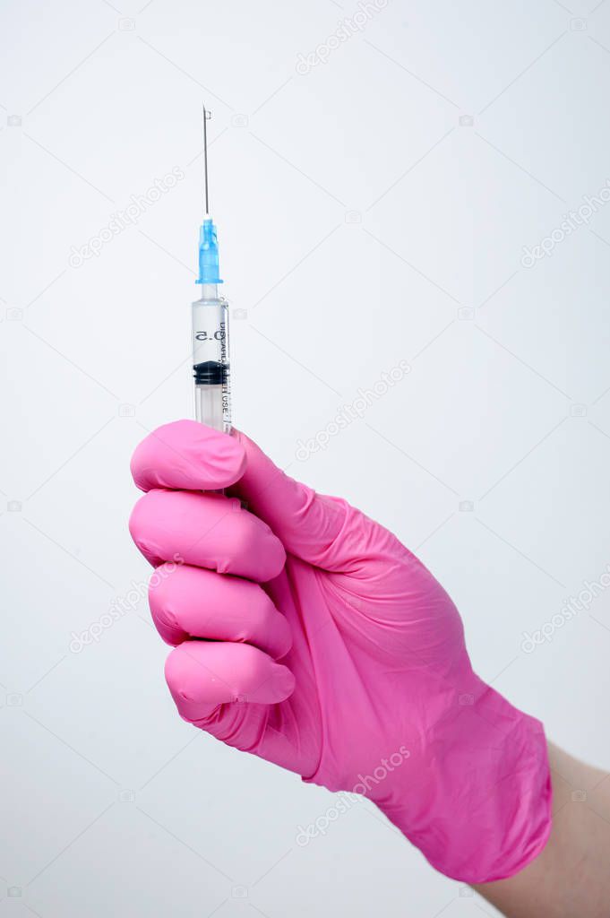 Syringe in hand in medical pink glove. Injectable vaccination. Medicine