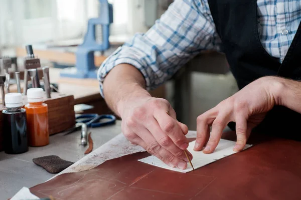 Male hands of master cutting with a knife pattern from genuine leather. Hand-made leather goods manufacturing — Stock Photo, Image