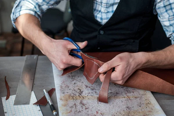 Young male craftsman working on cutting scissors, making leather goods — Stock Photo, Image