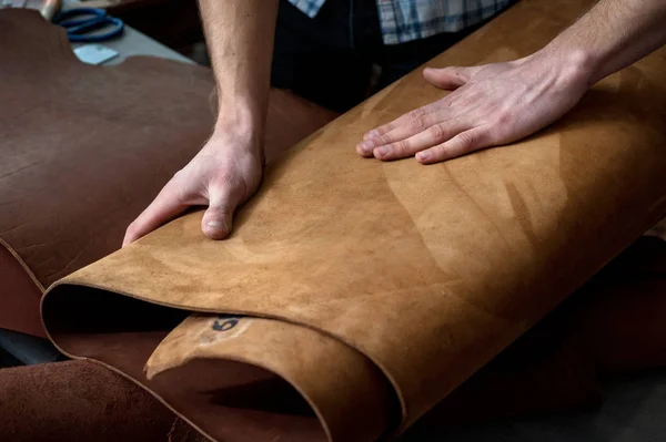 Hands of a craftsman on leather rolls. chiaroscuro artistic, suede — Stock Photo, Image