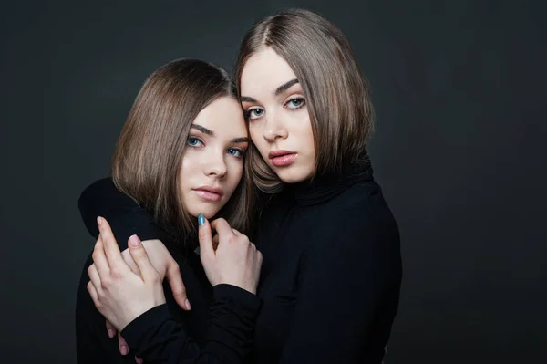 Portret dwóch dziewcząt w ramionach na ciemnym tle, starsza siostra, rodzina lub przyjaźń — Zdjęcie stockowe