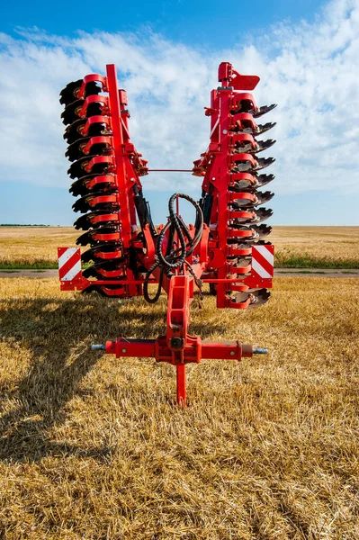 Kızıl Harrow toprağı işlemek için taşınmak üzere katlandı. Sahada harrow ve güzel gökyüzü arkaplanı