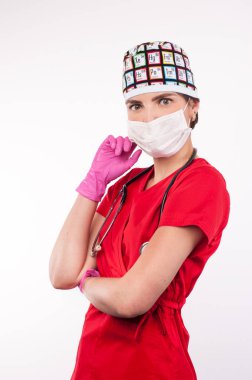 Maskeli ve steteskoplu çekici bir kadın doktor beyaz arka planda duruyor.