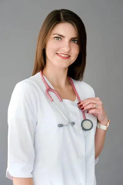 smiling female doctor with phonendoscope, kindness and professionalismover gray background
