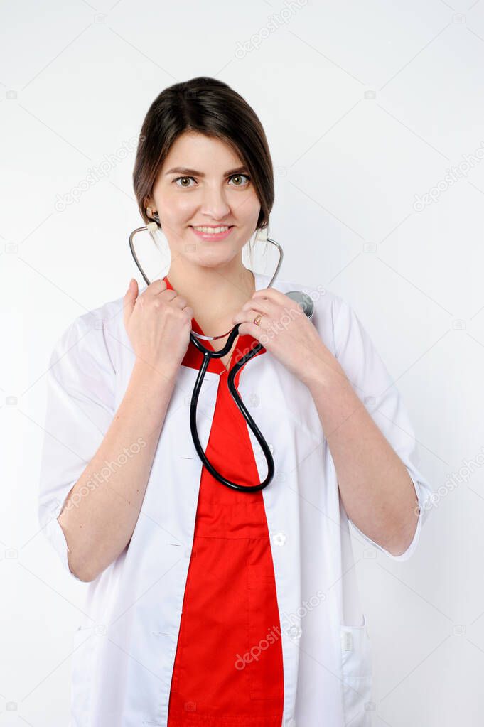 Portrait of smiling lady medical professional in white coat holding phonendoscope looking directly at the camera