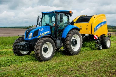 Bilohir 'ya, Khmelnytsky bölgesi, Ukrayna - 15 Ağustos 2019: Tarım teknolojisinin sunumu - New Holland, yeni mavi traktör T5.110S ile Baler Roll kemeri 180 ile tarım sergisi FARM Day' de tanıtım alanında hareket halinde.