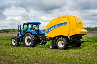 Bilohir 'ya, Khmelnytsky bölgesi, Ukrayna - 15 Ağustos 2019: Tarım teknolojisinin sunumu - New Holland, yeni mavi traktör T5.110S ile Baler Roll kemeri 180 ile tarım sergisi FARM Day' de tanıtım alanında hareket halinde.