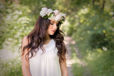 Bahar çelengi ve beyaz elbisesi olan güzel kız.