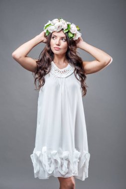 Gri bir arka planda izole edilmiş şakayık çelenkli seksi gelinin bahar portresi..